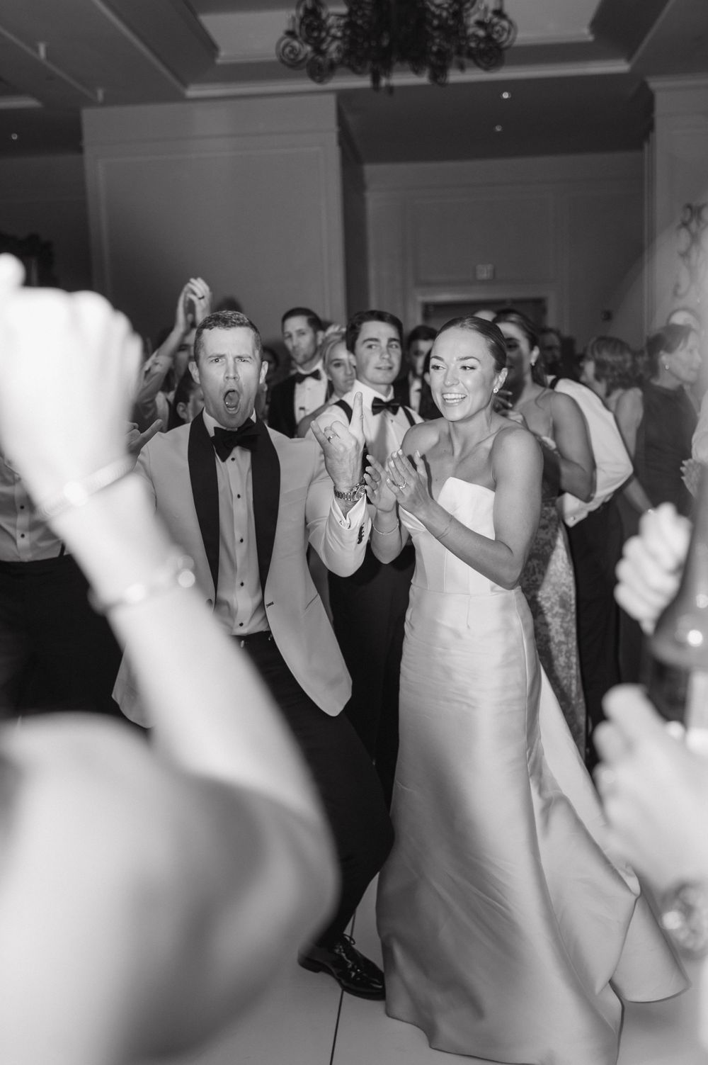 Wedding guests dancing together on a crowded dance floor at a reception celebration.