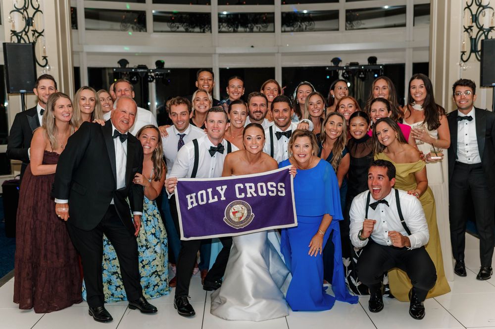 Large group of wedding guests pose together on a dance floor at a formal reception celebration.