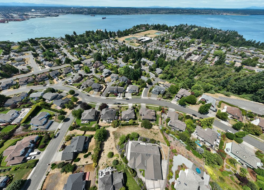 Aerial view of residential neighborhood near waterfront with winding streets and homes overlooking bay in Pacific Northwest.