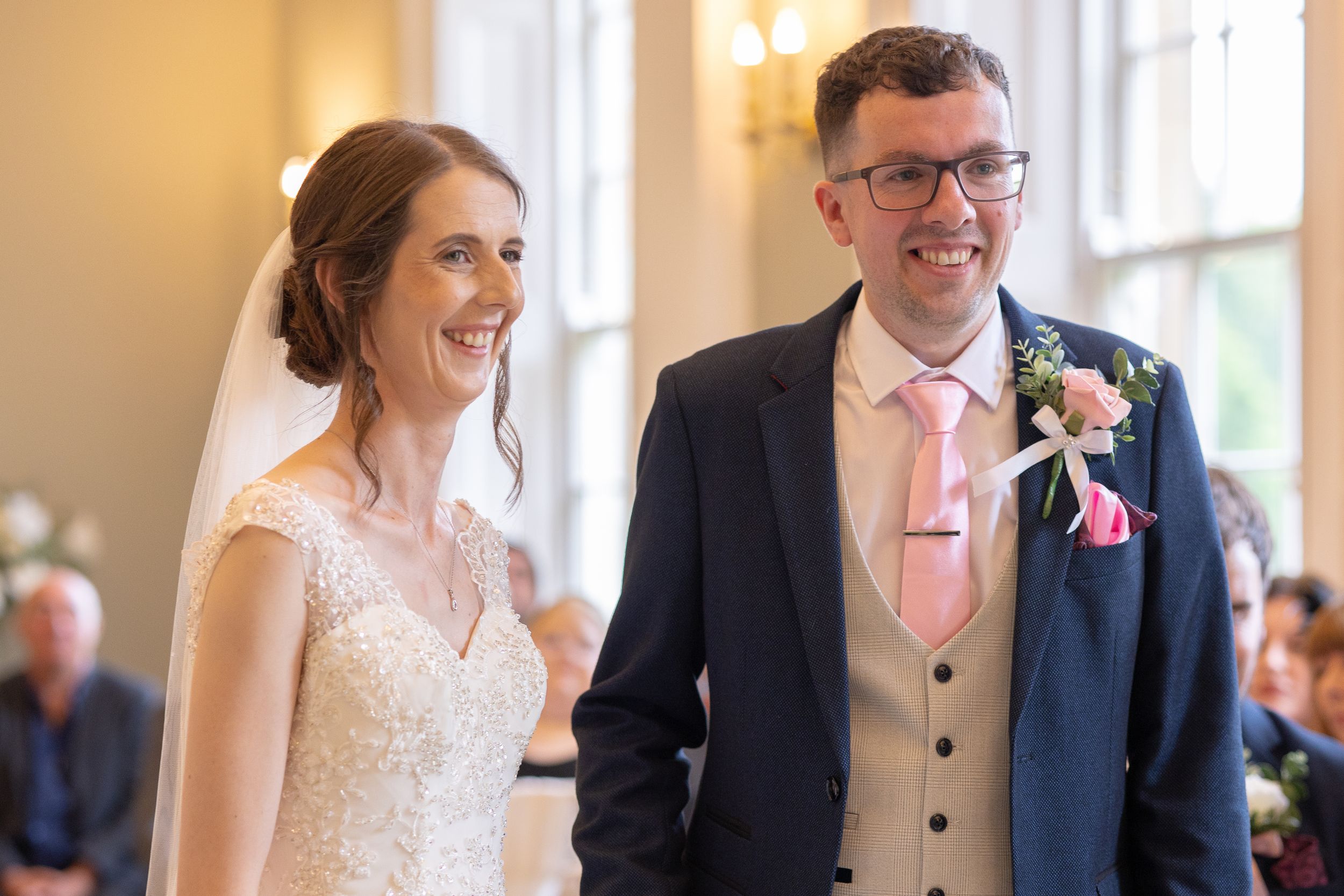 Happy newlyweds share a joyful moment together during their wedding ceremony in an elegant indoor venue.