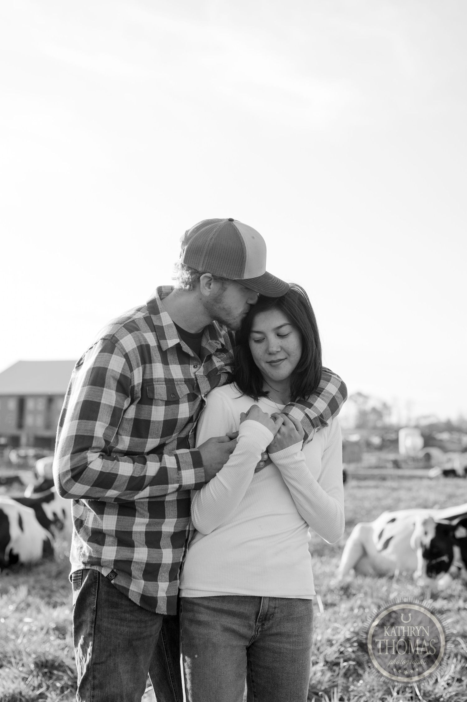 A black and white portrait of a couple sharing an intimate moment on their farm property.