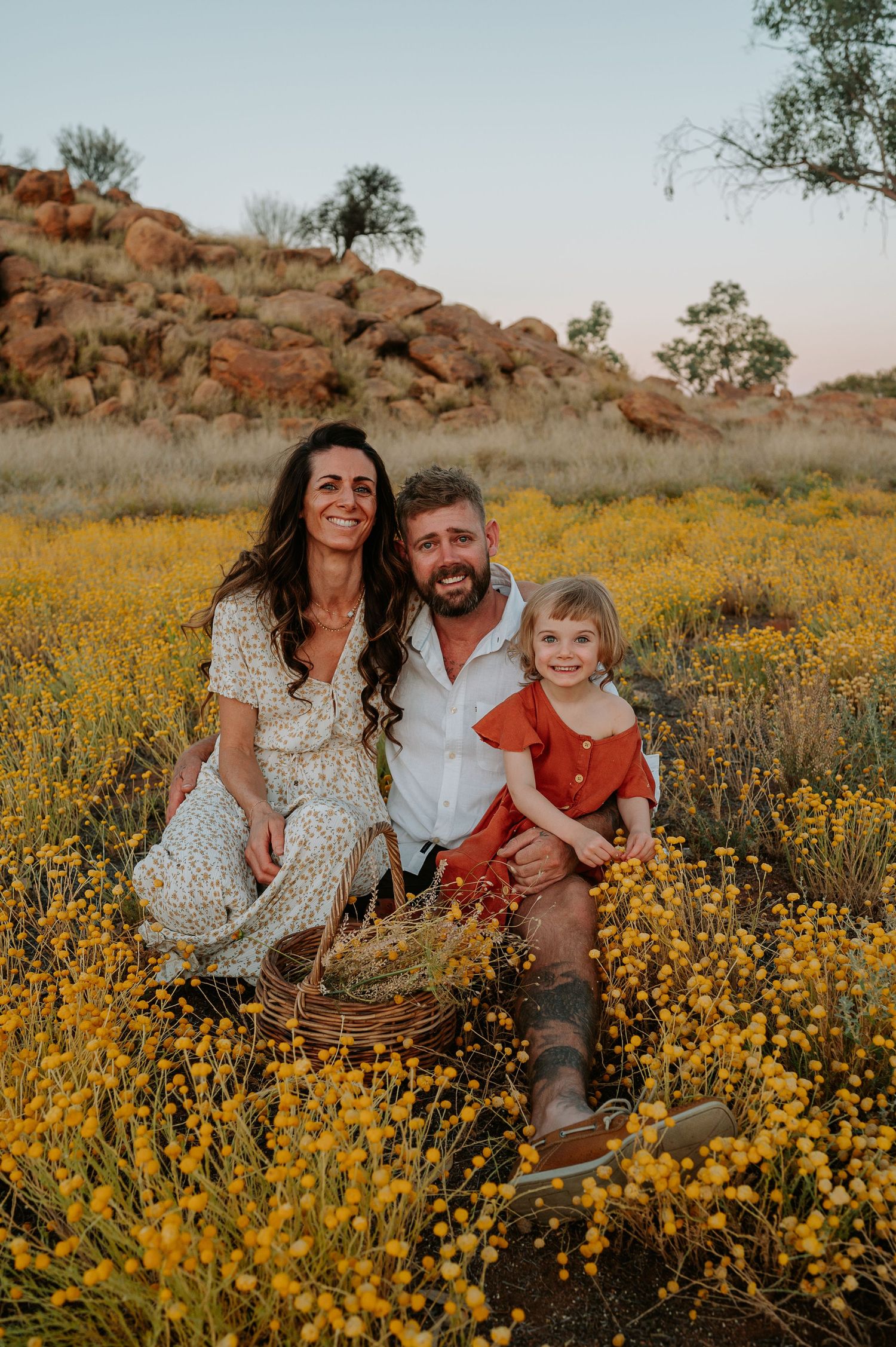 Mother, father and daughter sit in field of flowers - Alice Springs