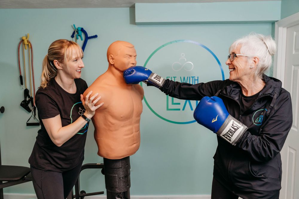 Three people practicing boxing techniques with a training dummy in a light blue gym room.