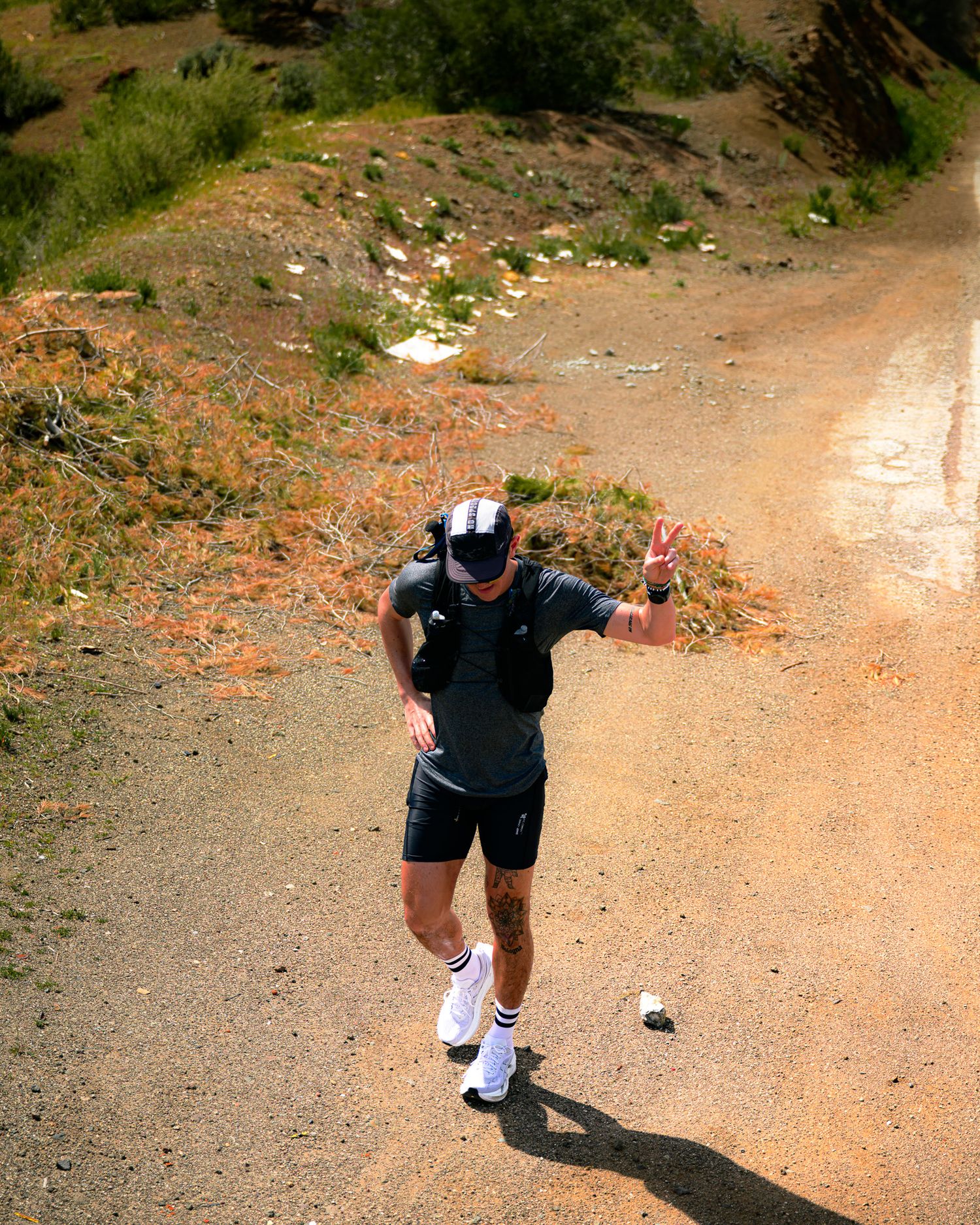 Runner posing victoriously on a dirt trail with dramatic mountain backdrop.