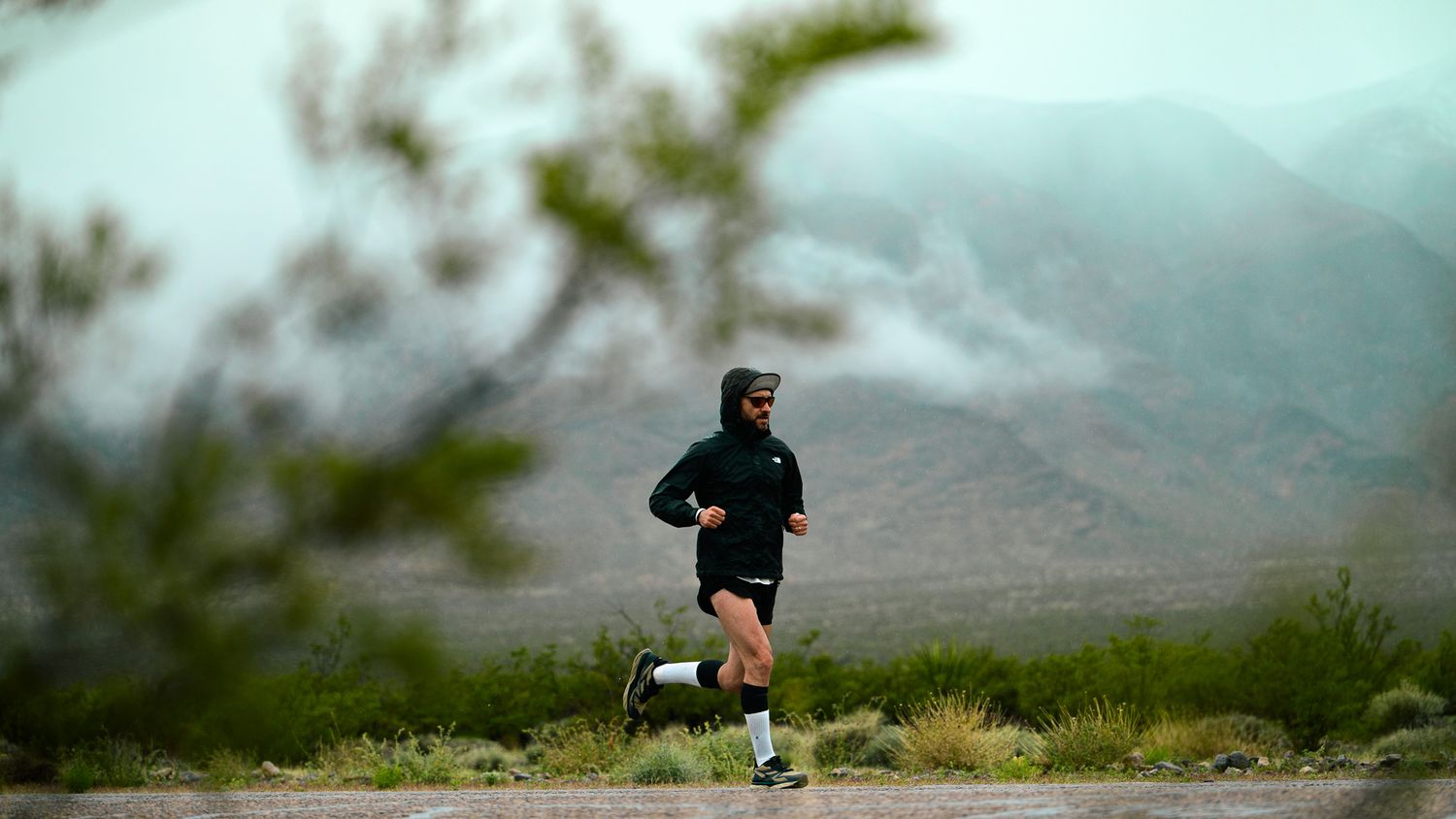 Silhouetted runner against a misty mountain landscape.