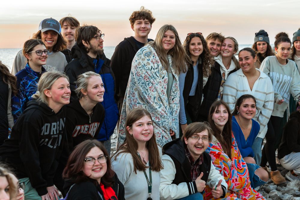 Large group of people gathered together outdoors at sunset.