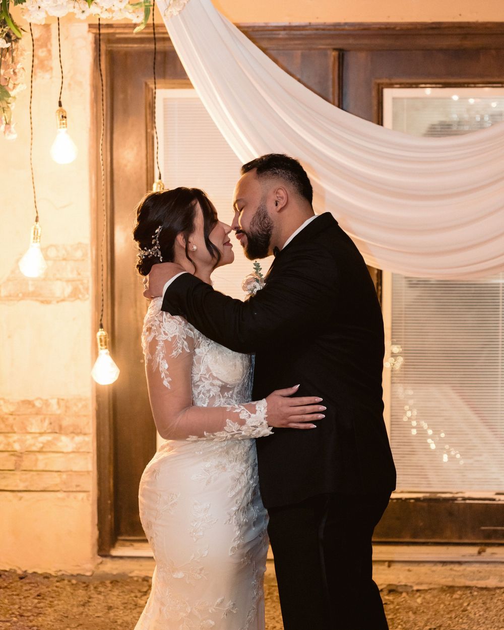 Bride and groom slow kissing during wedding reception under warm lights
