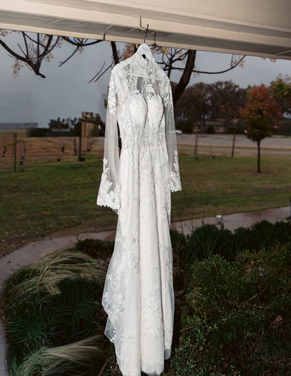 Bride’s wedding dress hanging outdoors before ceremony, romantic bridal detail