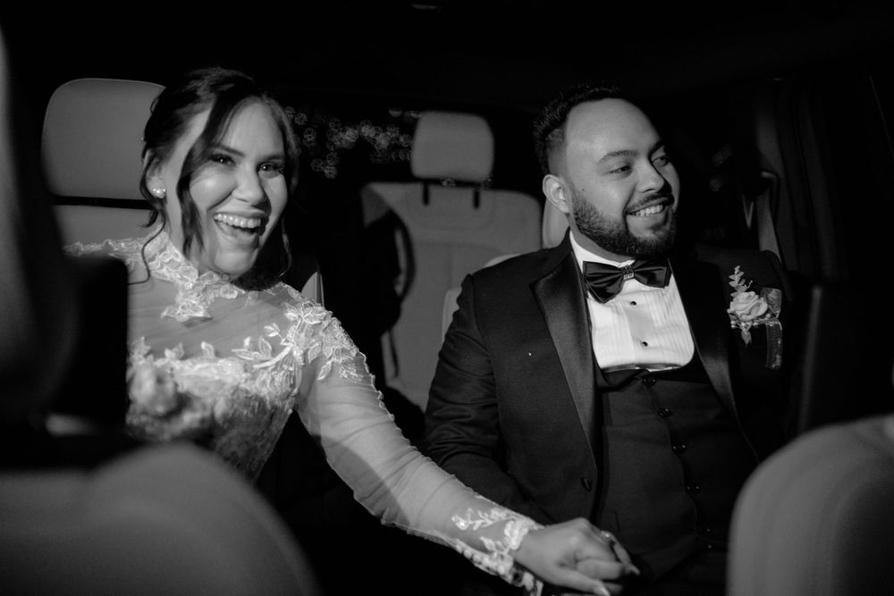 Bride and groom laughing together during wedding reception, candid black and white moment