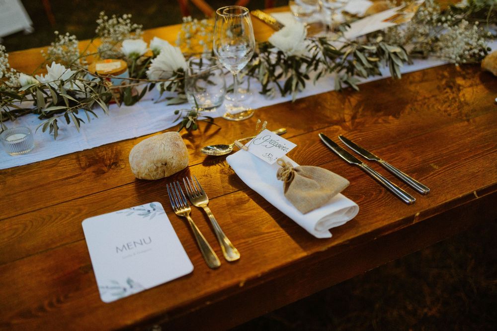 A rustic wooden dining table set with elegant place settings and glowing candlelight creates an intimate atmosphere.