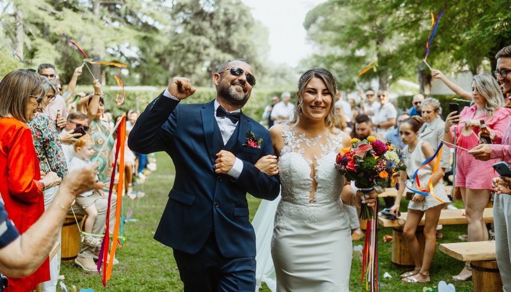 Happy couple celebrates their joyful exit down the aisle amidst a cheering crowd at an outdoor garden wedding ceremony.