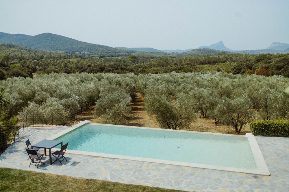 Infinity pool overlooking a scenic mountain landscape with olive groves.