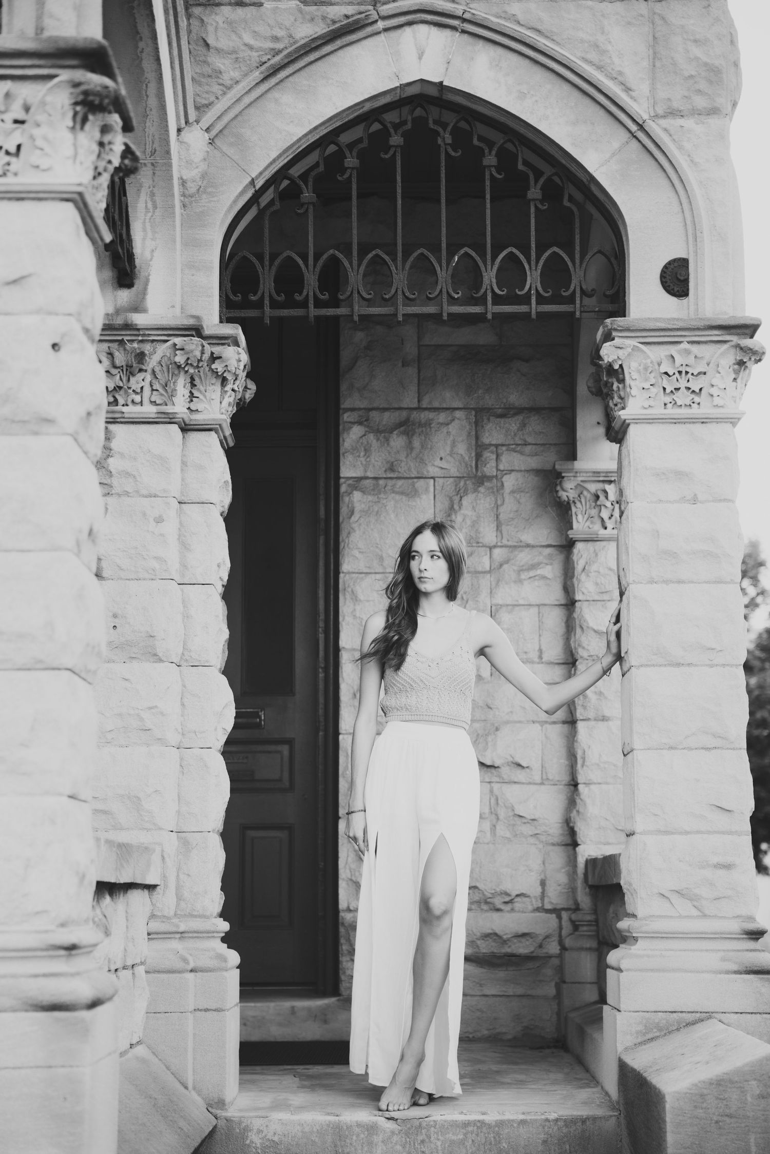 Black and white senior photo with stone archways and columns.