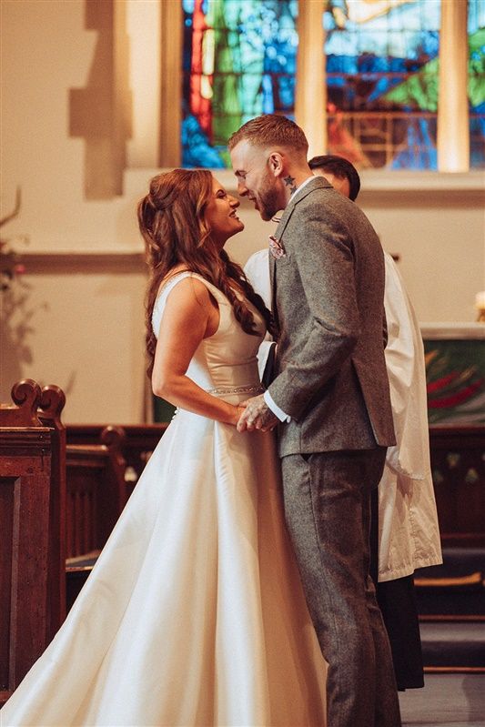 Bride and groom sharing a joyful moment at church altar.