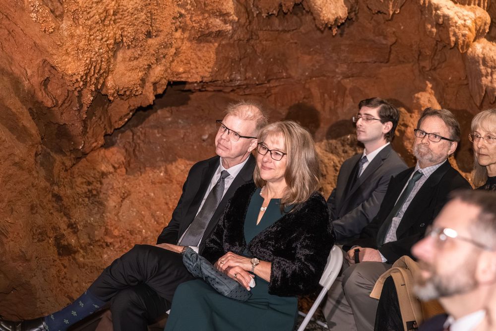 Guests seated in a cave wedding venue, watching the ceremony among dramatic natural rock formations.