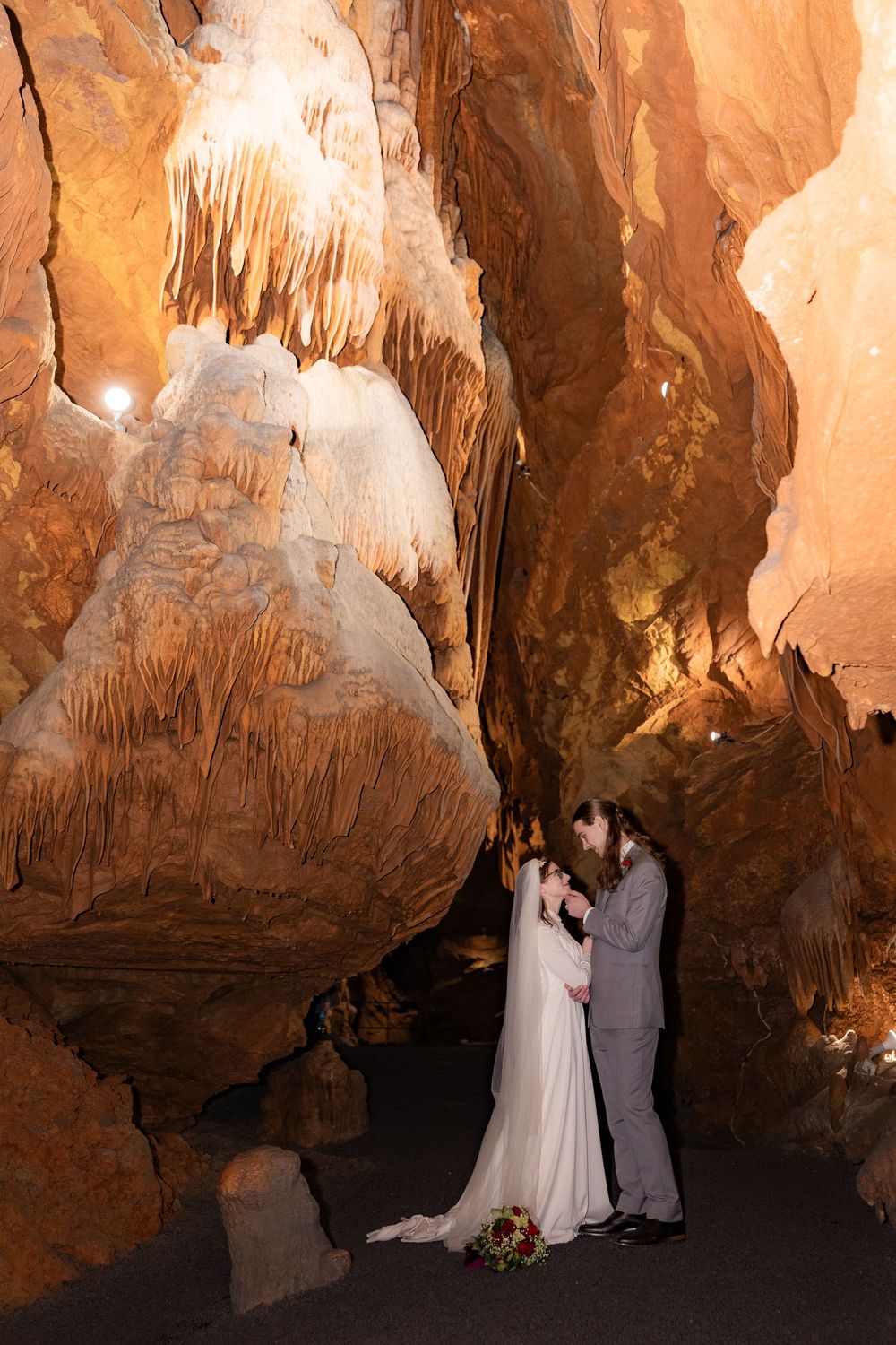 Bride and groom share a romantic moment during a cave wedding ceremony surrounded by stunning stalactite formations.