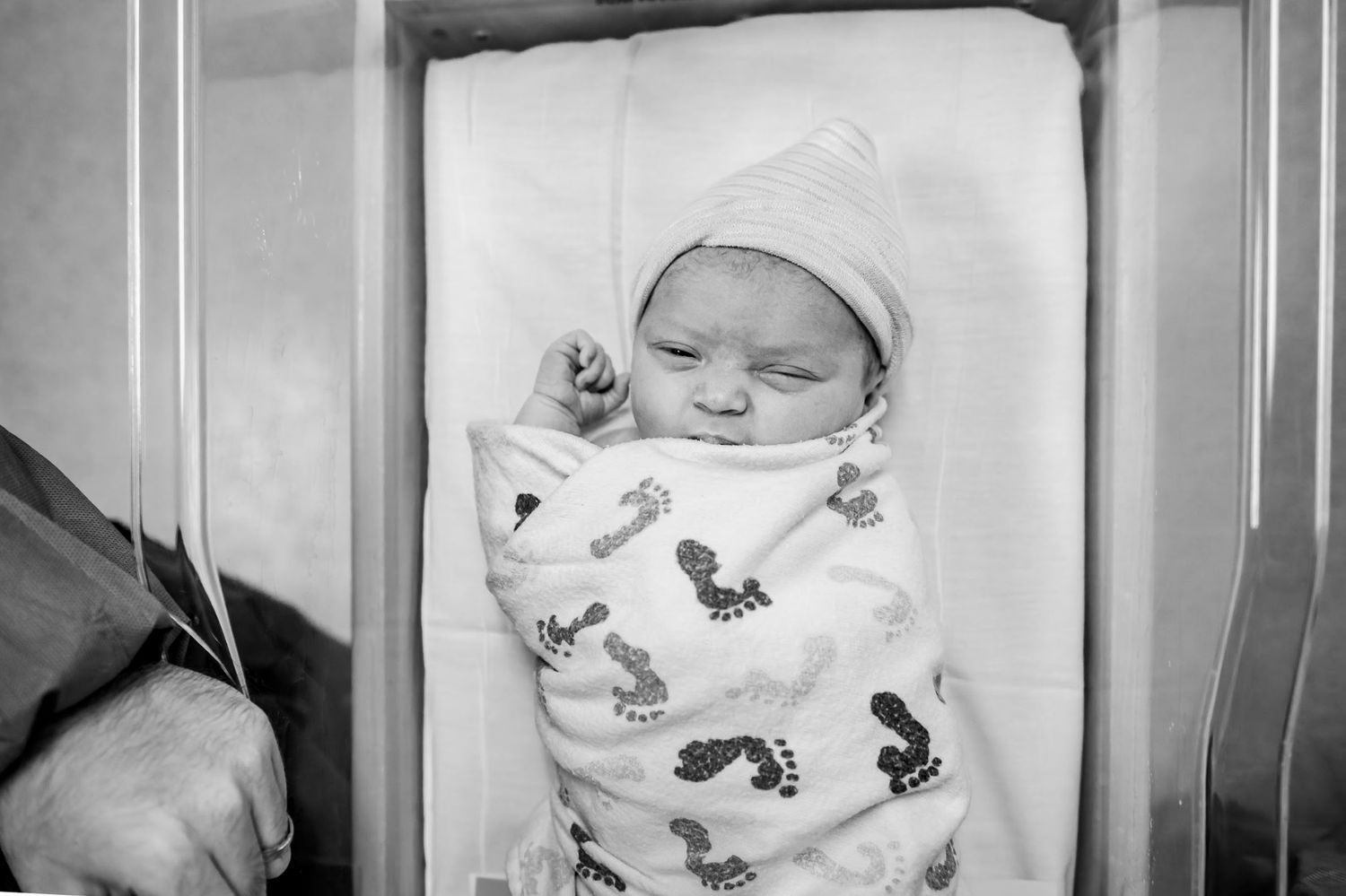 A sleeping newborn baby swaddled in white with butterfly print material rests peacefully.