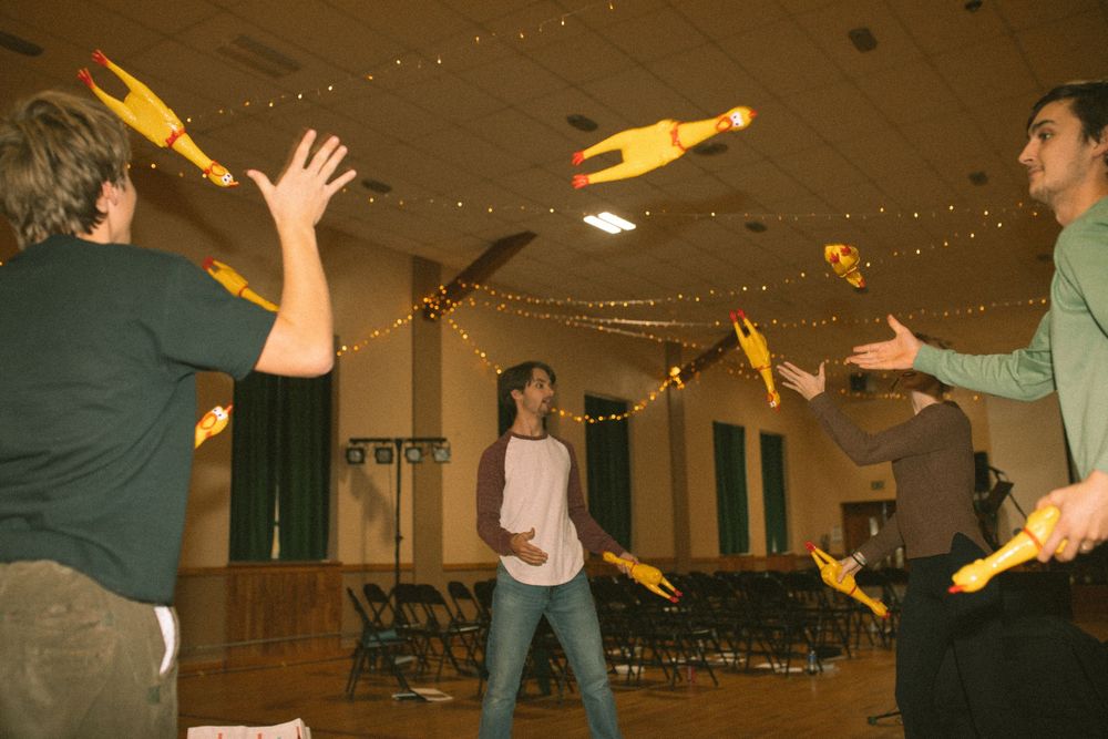 People juggling yellow pins in a decorated indoor hall during a group activity.