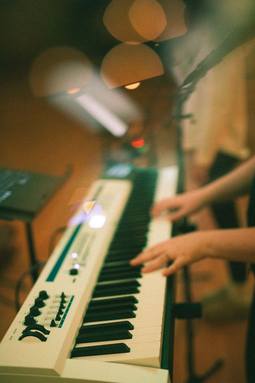 Hands playing white Casio keyboard synthesizer at live music performance event.