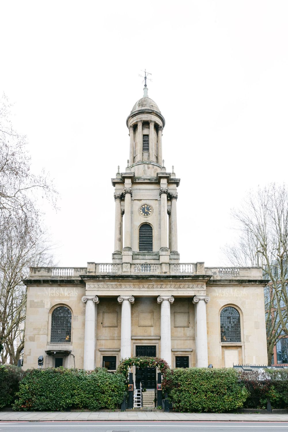 A neoclassical church with grand columns, arched windows, and a domed bell tower surrounded by bare winter trees.
