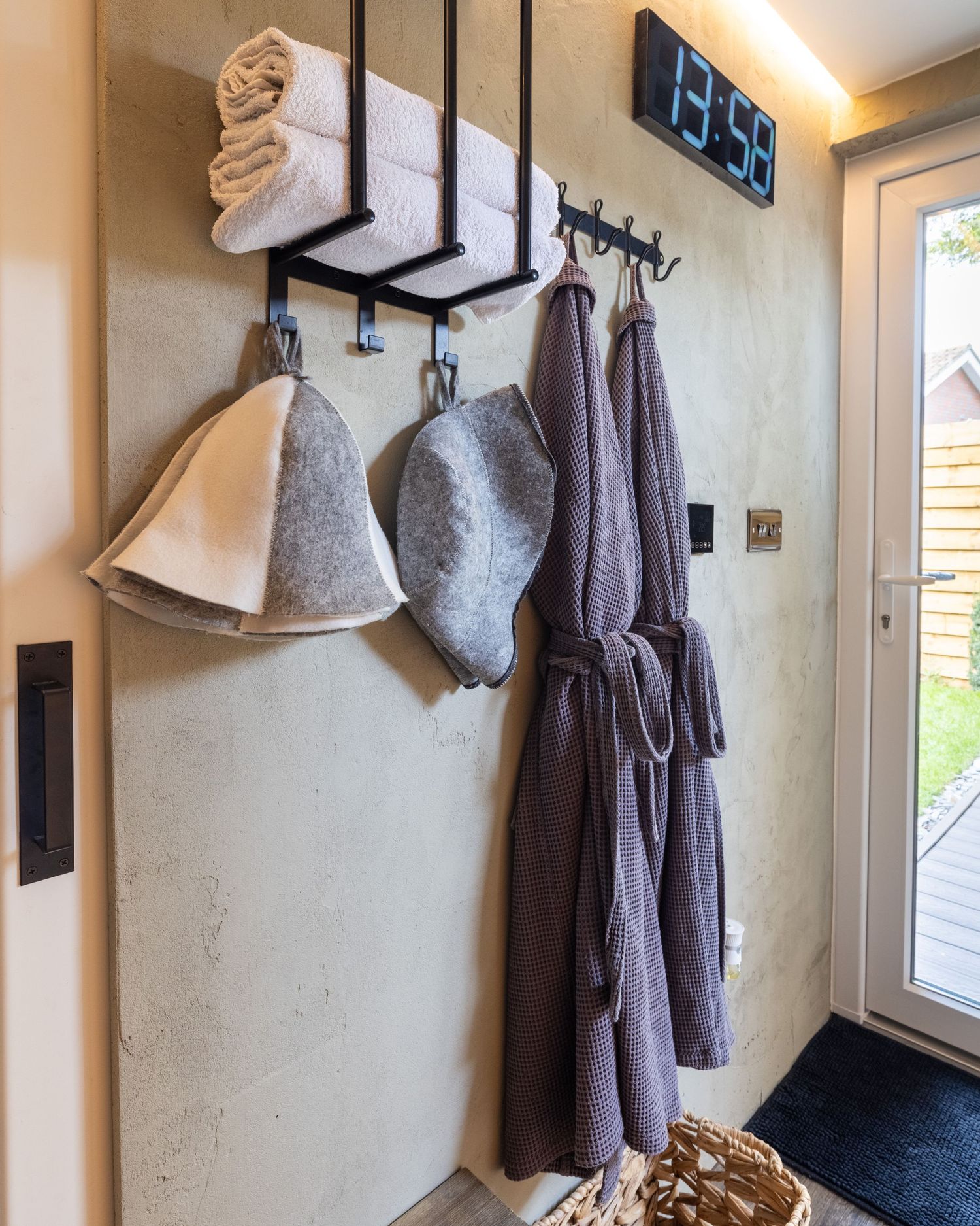 Spa entryway in Bedfordshire with hanging robes, sauna hats and folded towels on wall hooks, photographed during a professional spa shoot.