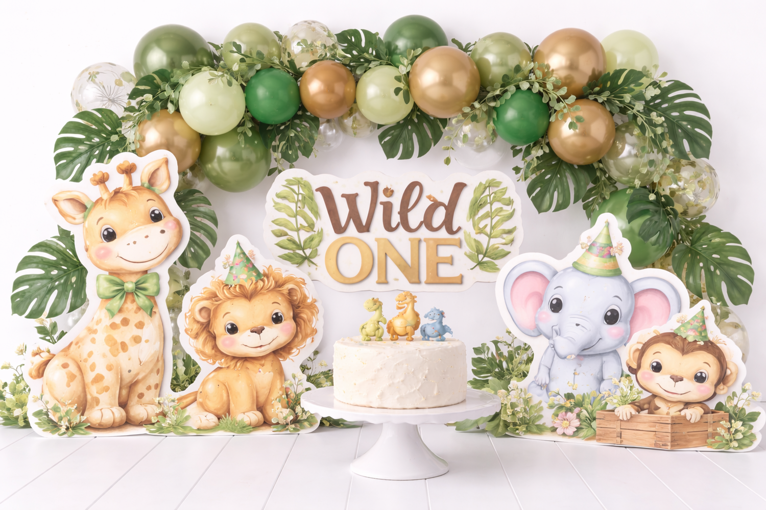 Wild One safari first birthday party setup with jungle animals, green and gold balloons, and a white cake centerpiece.Elizabeth Lang