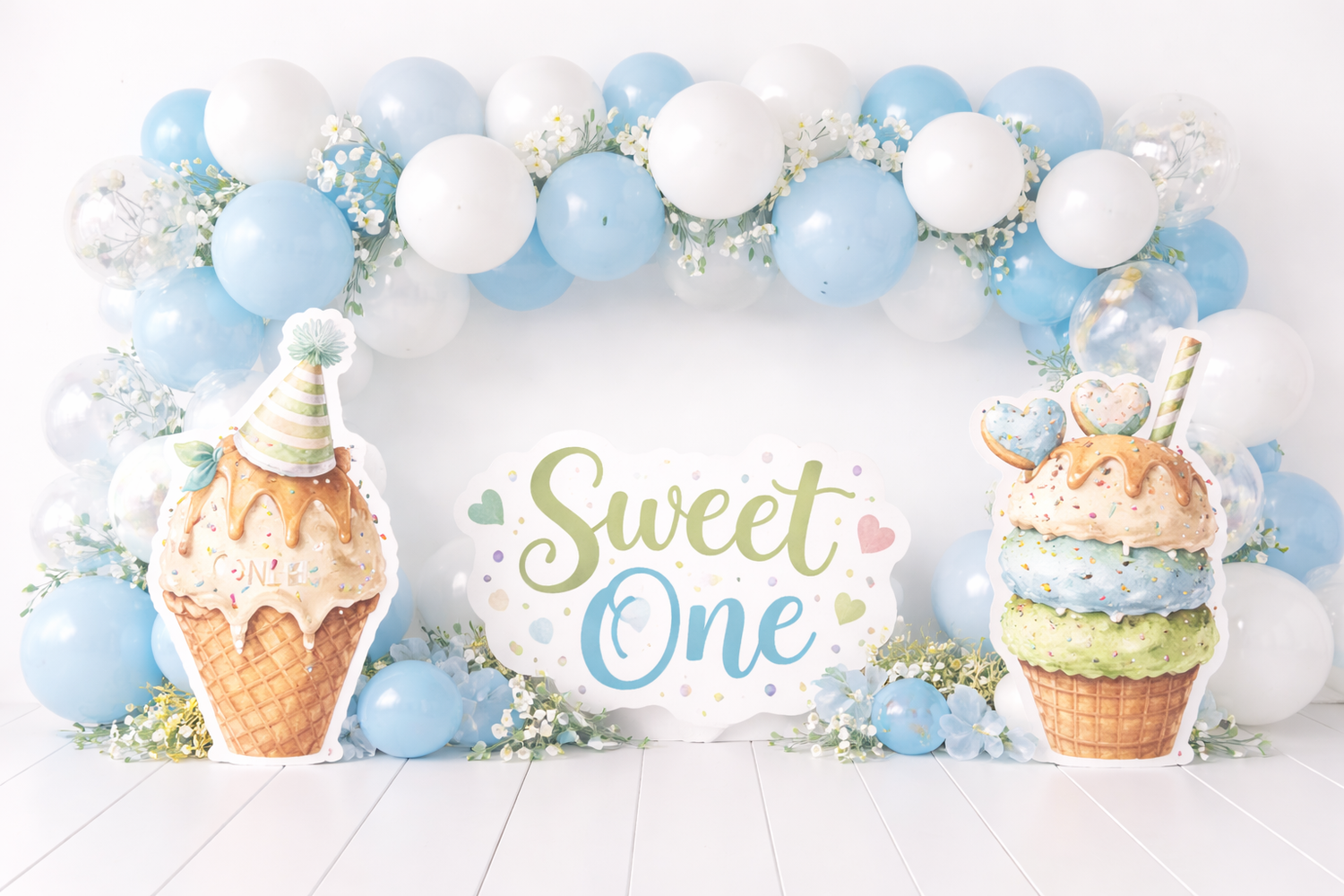 Sweet One first birthday backdrop with blue and white balloon arch, ice cream cone cutouts, and floral decorations. Elizabeth Lang