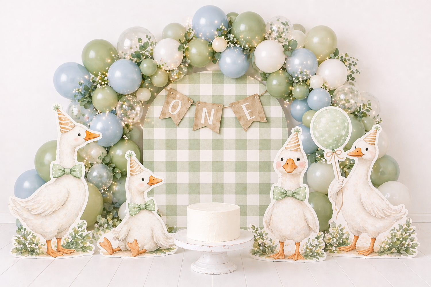 First birthday cake smash setup with goose cutouts, green gingham backdrop, and sage green and blue balloon garland.