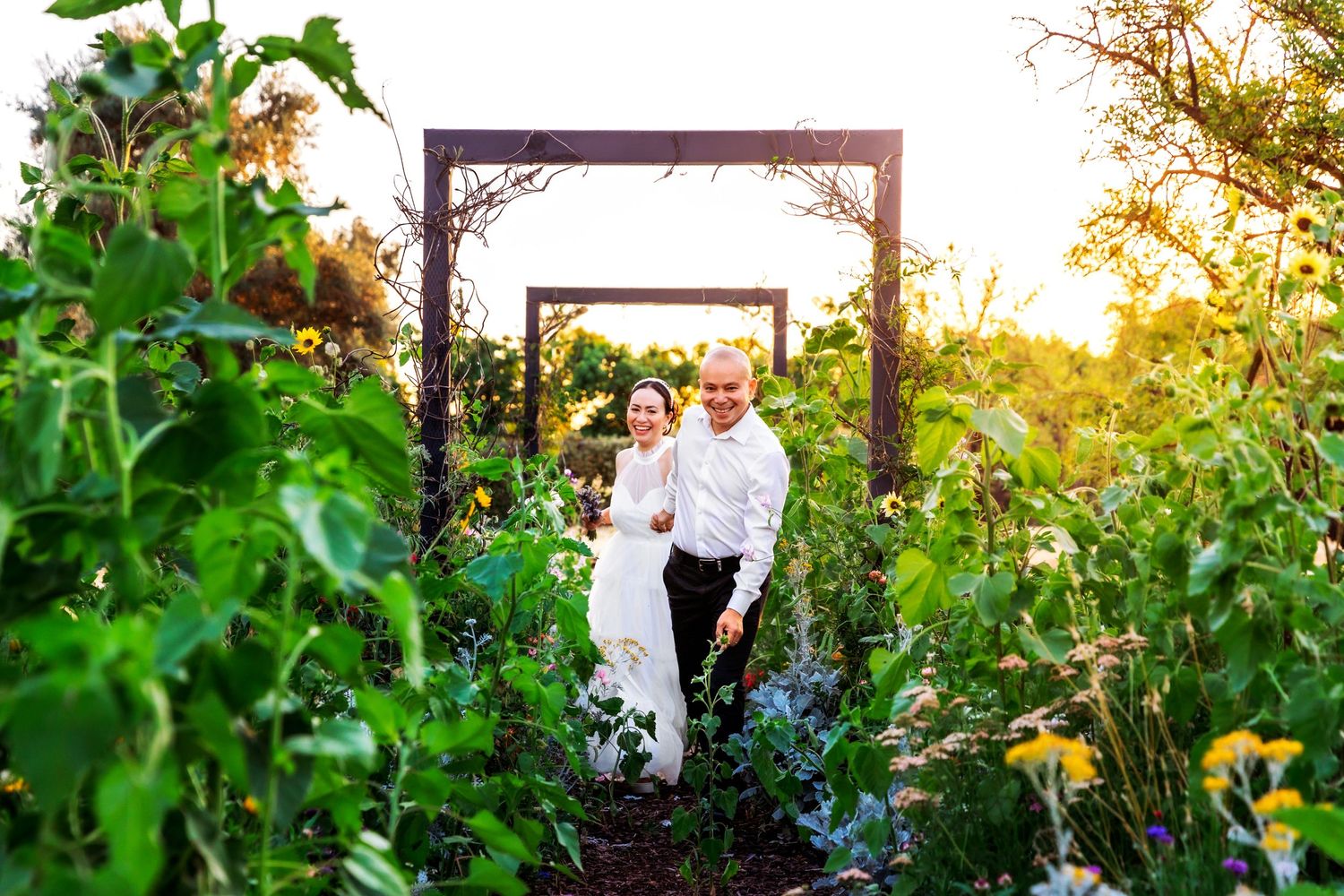 Photographer takes fun filled shot of happily engaged couple in colorful garden in full bloom at  Fresno, CA.
