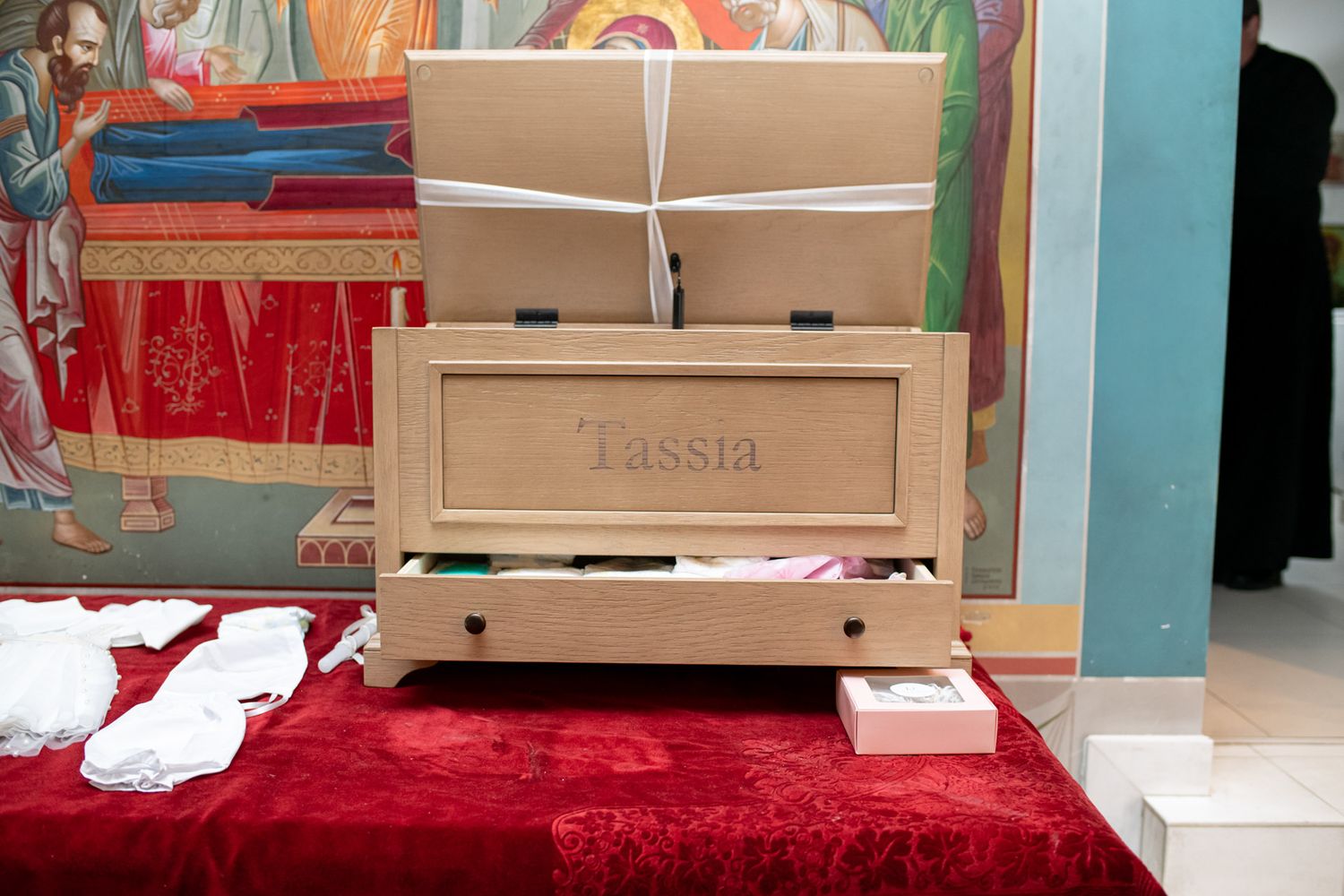 A wooden keepsake box engraved with the name Tassia displayed on a red velvet surface.