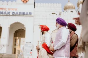 Traditional Sikh wedding ceremony attendees wearing colorful turbans gather at temple entrance.
