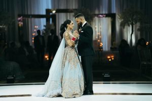 A couple shares an intimate moment during their first dance at a wedding reception illuminated by candlelight.