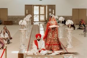 Traditional Indian wedding ceremony featuring ornate decor with crystal pillars and a couple in red and ivory attire.