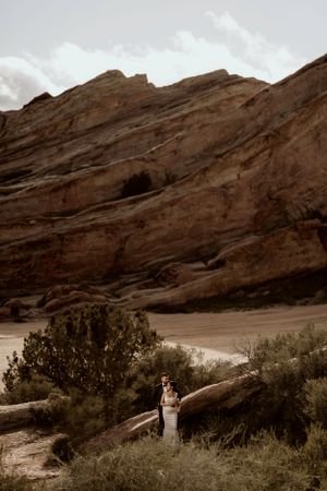 A romantic moment captured against majestic red rock formations at Red Rocks Park, with desert brush in the foreground.