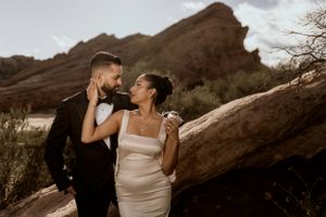 A joyful couple shares a candid moment in front of striking red rock formations.