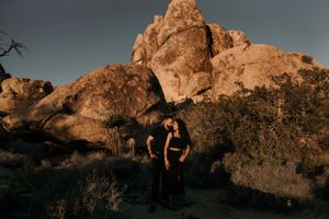 Couple embracing at sunset among large rock formations in Joshua Tree National Park.