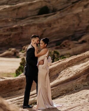 Intimate moment between couple in formal wear against red rock formations.