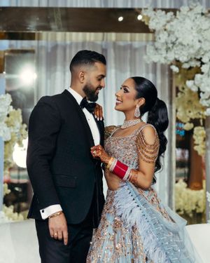 A couple shares an intimate moment at their wedding reception surrounded by elegant white floral decorations.
