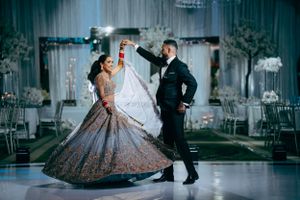A couple shares their first dance at an elegant wedding reception with a glittering ballgown twirling on the dance floor.