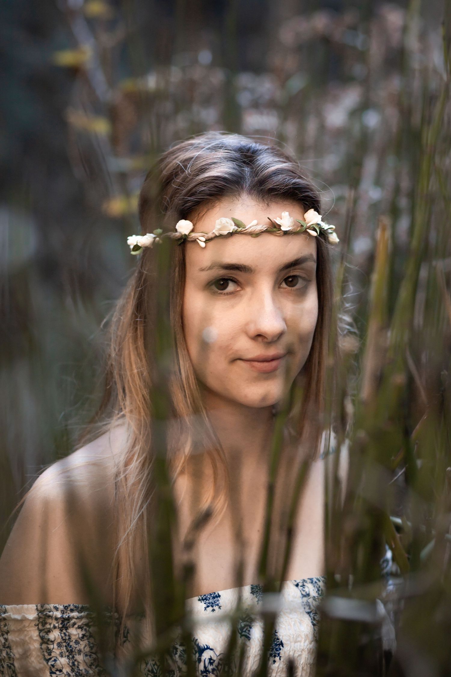 Girl with flower crown staring through blurred tall brush on Maui