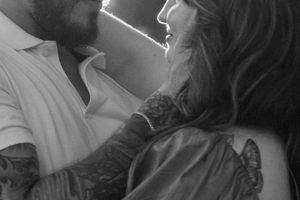 A black and white photo showing a close intimate moment between two people in soft lighting.