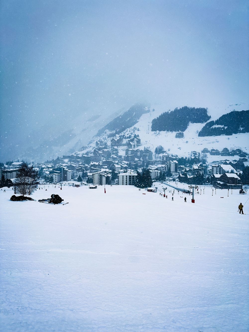 Snow-covered ski resort town nestled in mountains under a winter sky.