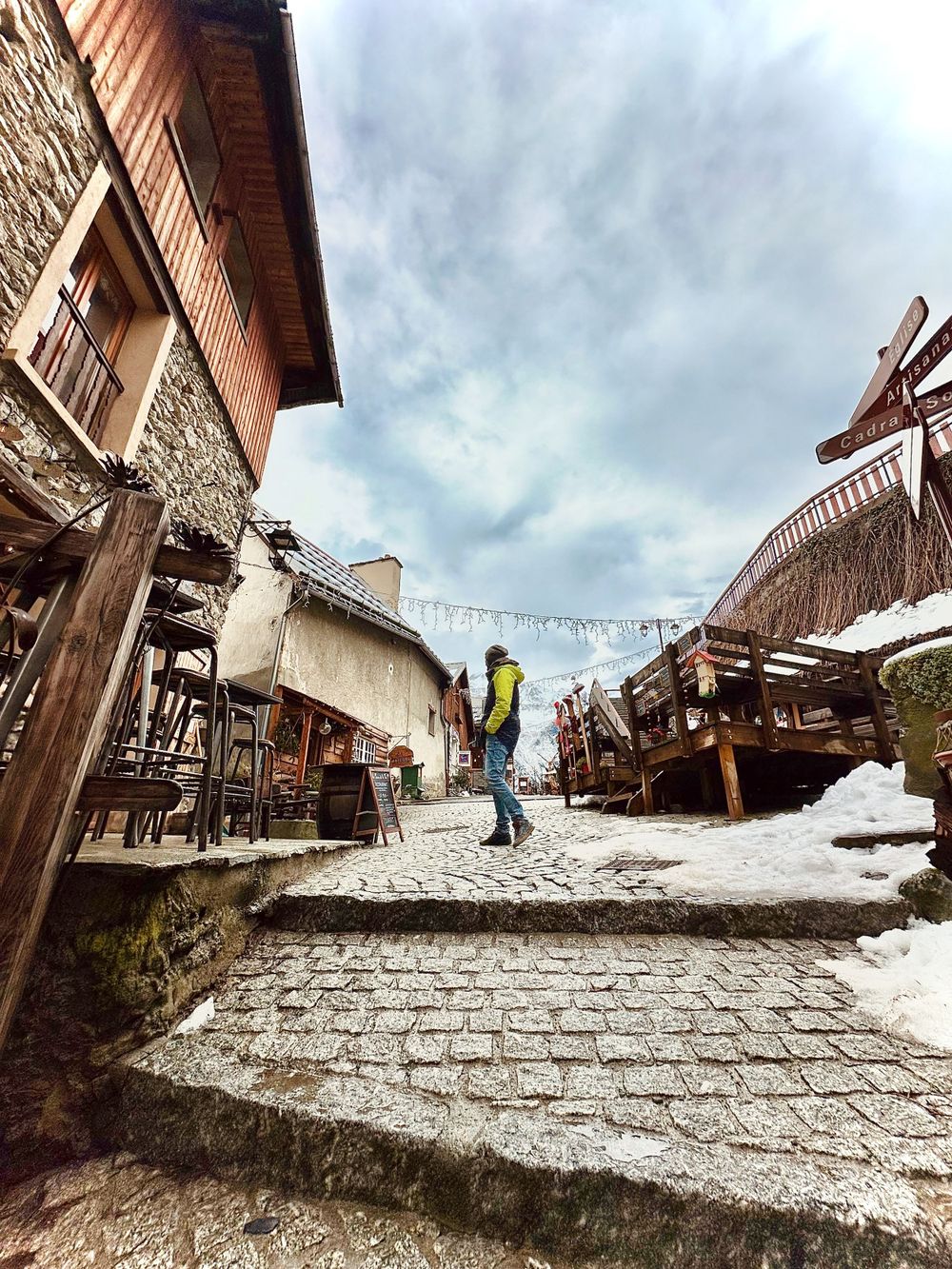 Snow-covered medieval marketplace with wooden stalls and stone buildings.
