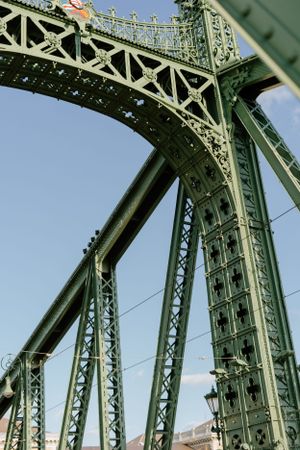 Close-up architectural view of green painted metal trusses and ornate details on the historic Liberty Bridge in Budapest.