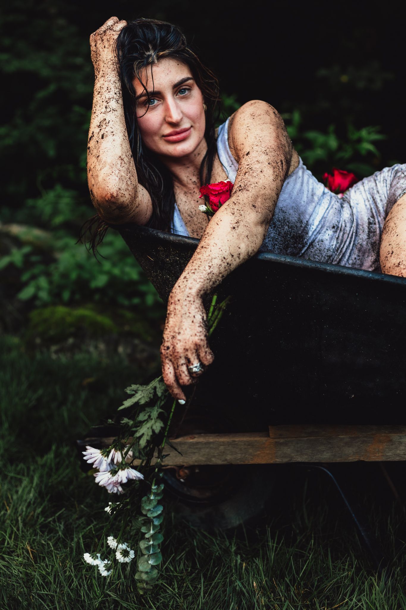 woman in wheelbarrow holding flower, emotional, raining, garden, dramatic, lifestyle, creative photoshoot, themed