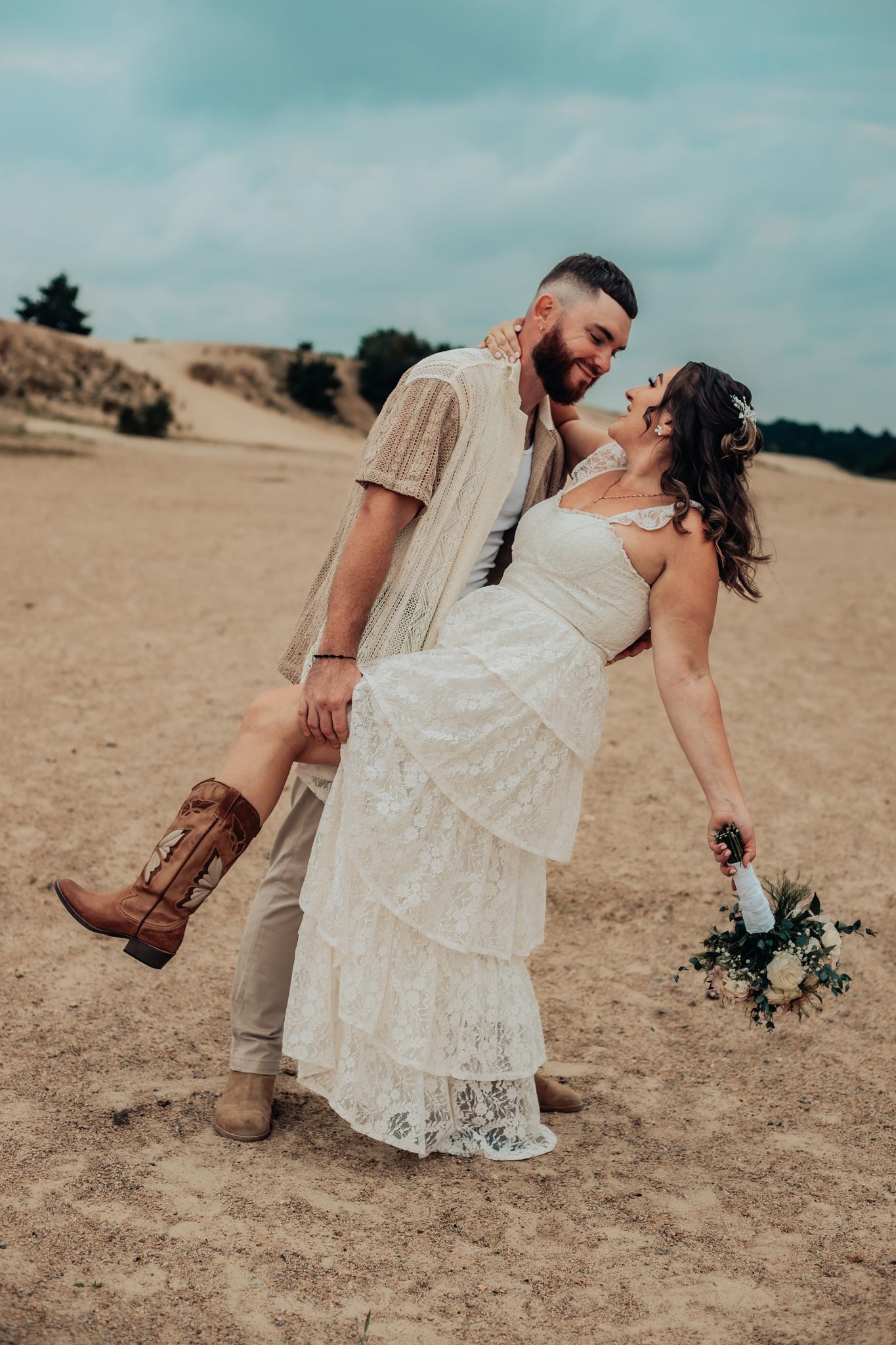 groom dipping his bride at the sand dunes