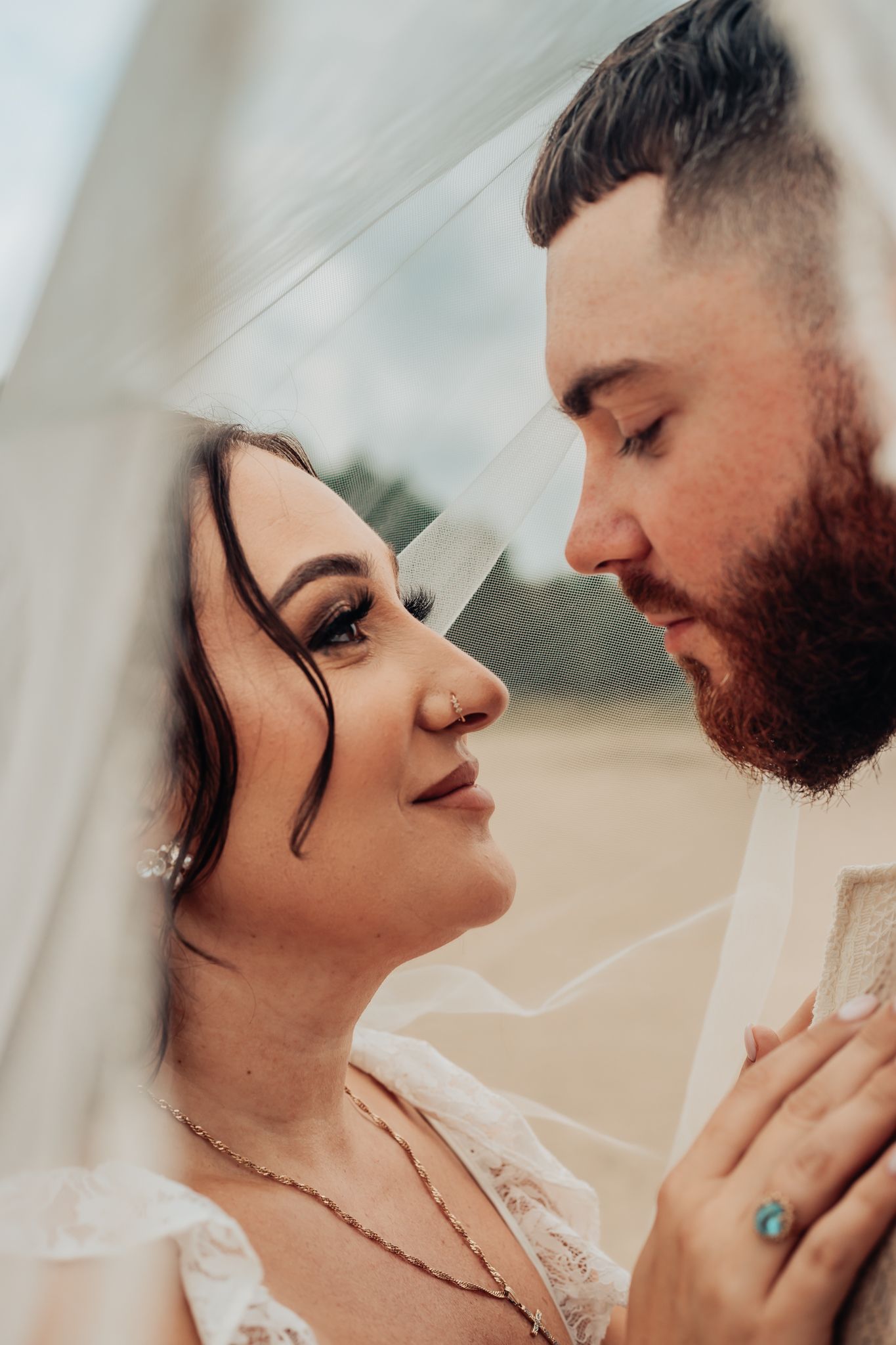 bride and groom under a veil at the sand dunes