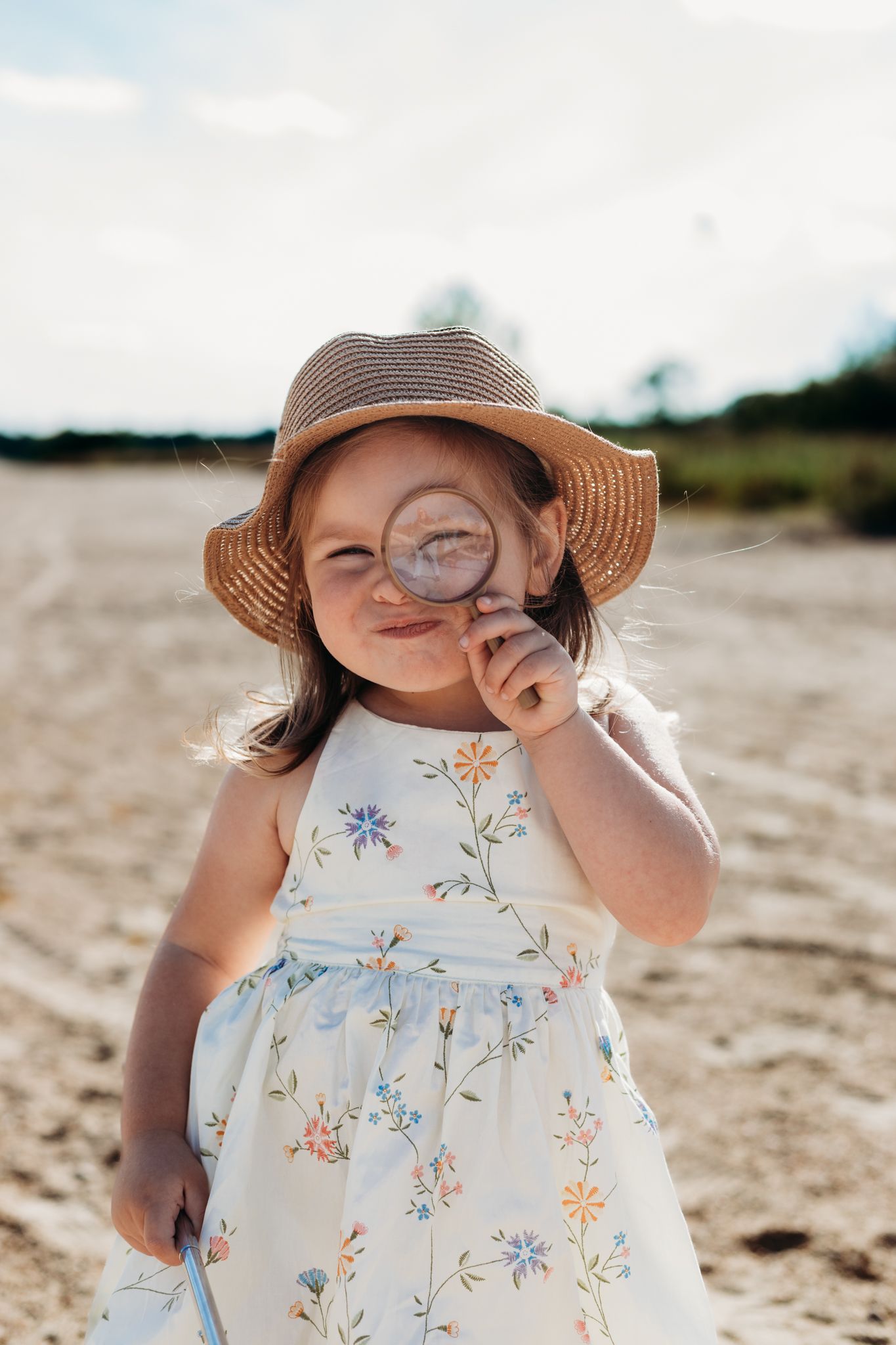 girl holding magnifying glass at sand dunes