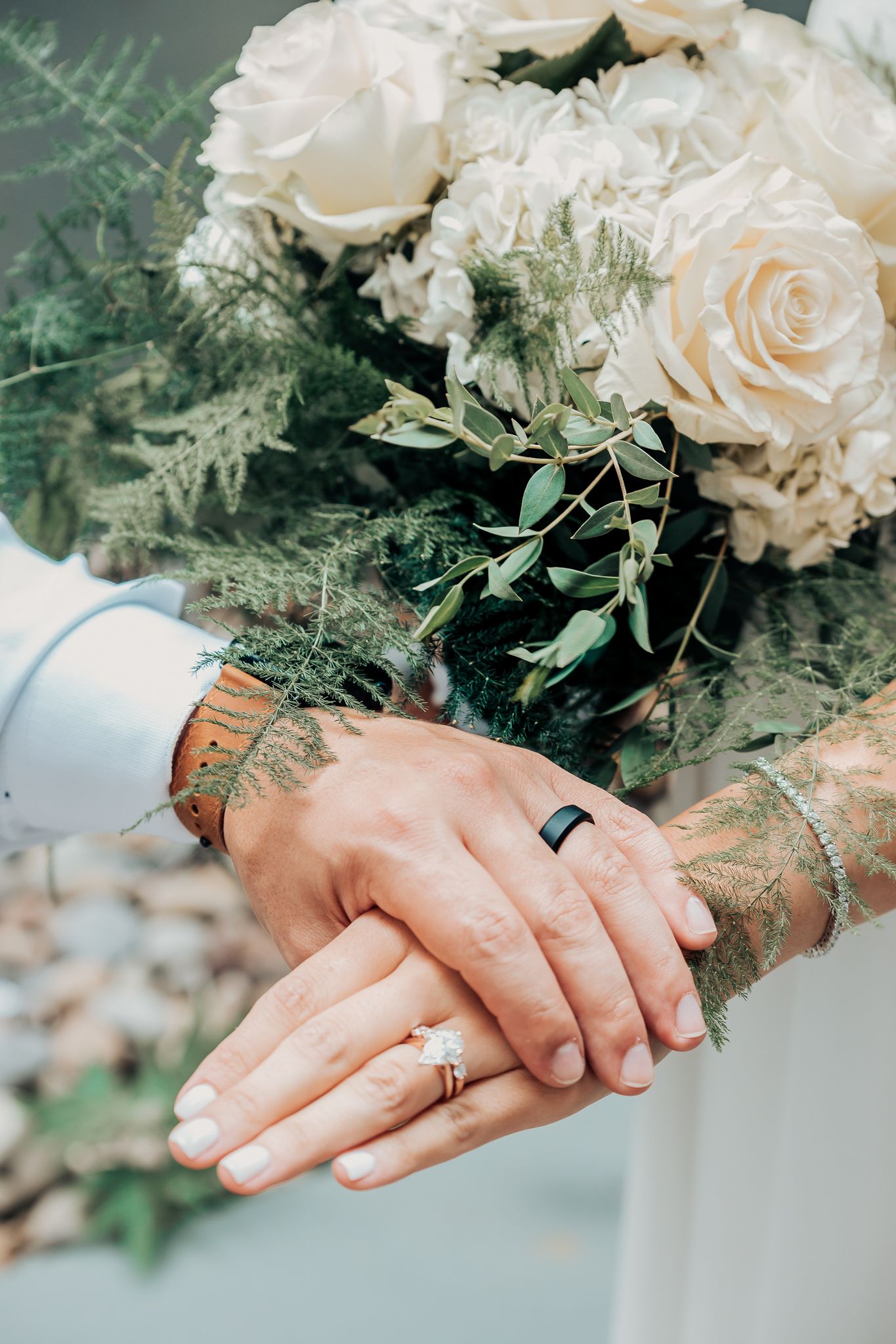 bride and grooms wedding rings, holding hands and flowers