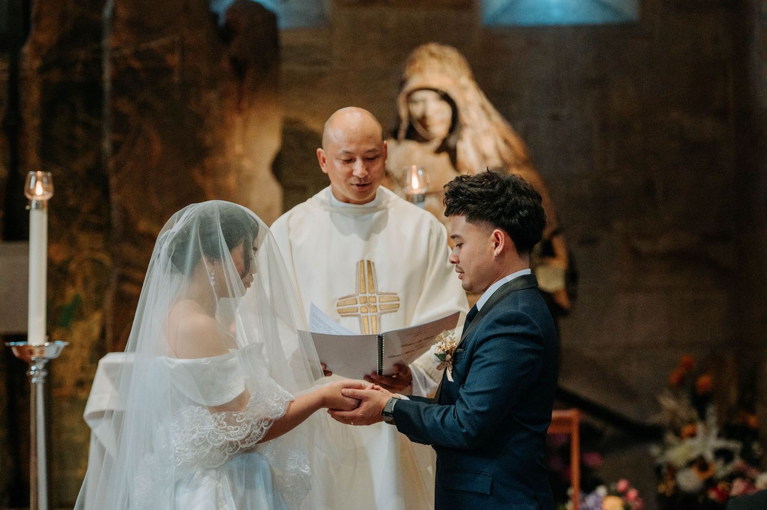 Priest officiating ring exchange ceremony during traditional church wedding.